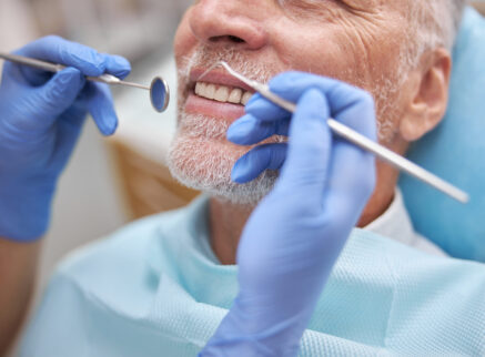 A man with a gray beard having his teeth cleaned